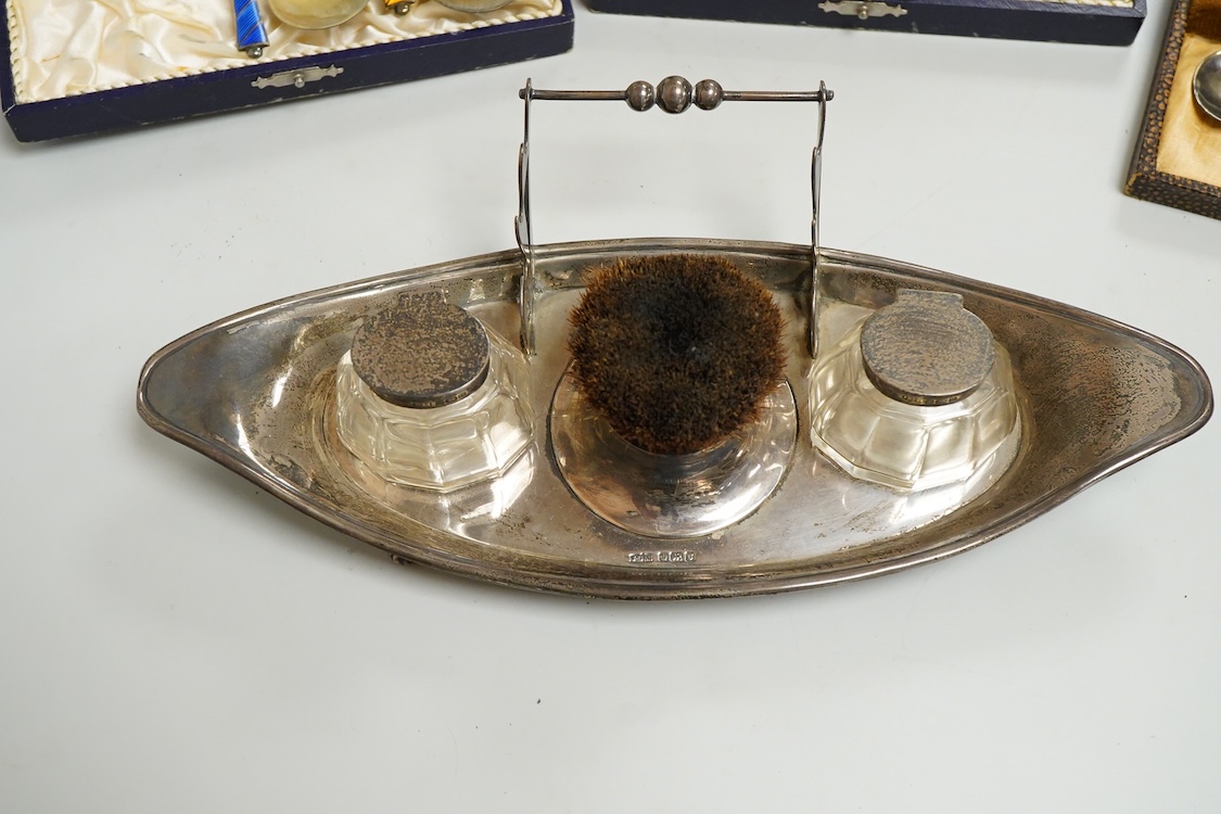 An Edwardian silver elliptical shaped inkstand, with two mounted glass wells and central pen wipe, James Dixon & Sons, Sheffield, 1906, together with ten Danish sterling and polychrome enamel spoons(a.f) and a cased set